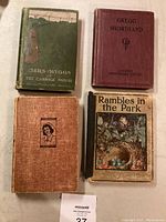 Top-down view of four antique books arranged on a table showing covers, titles, and condition.