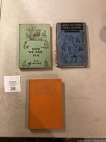 Three antique books laid flat with view of front covers showing titles and illustrations.