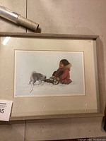 Framed print showing a child in winter clothing with a dog playing in snow.