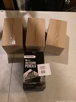 Three large cardboard boxes with multiple packs of sketching pencils in front, showing quantity and packaging size.