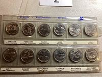 Front view of twelve 25 cent Canadian coins from 1992, in a sealed plastic holder, each coin representing a month and province or territory.
