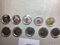 Top view of 10 collectible coins in protective cases showing colorized and silver-tone coins with various designs.