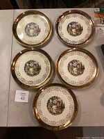 Five collectible plates arranged on table showing gold rim and central classical dance scene design.