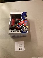 Front view of the boxed Mighty Muggs Transformers figure showing logo and character design visible through window.