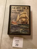 Front cover of the book showing colorful illustration of a tall sailing ship and whaling boat on ocean with title "Moby Dick the White Whale"