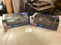 Two boxed Maisto model cars on table, showing front and sides of packaging