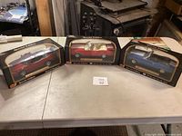 Three boxed Maisto Special Edition model cars, red, red, and blue, displayed on a table.