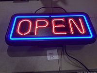Neon light sign glowing red 'OPEN' with blue border, hanging on the wall with chain, shown powered on.