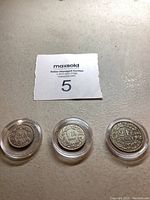 Three old collectible coins in plastic holders, front view showing dates and denominations.