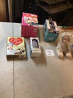Lot wide view of the assembled vintage items on display including doll and boxed collectibles