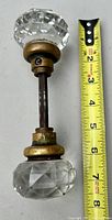 Full view of the antique glass knob attached to its brass fitting with measuring tape alongside indicating approx. 7 inches length