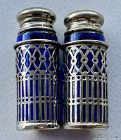 Front view of the antique salt and pepper shakers showing silverplate lattice design over cobalt blue glass inserts.