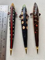 Three wooden pen fish decoys shown side by side with ruler to demonstrate size, approximately 6 inches long each.