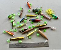 Top-down view of the full collection of 18 handmade, hand painted fishing lures arranged with a 12-inch ruler for scale.