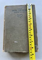 Front cover of book with tape measure for scale approximately 8 inches tall. Shows wear on cover edges and corners.