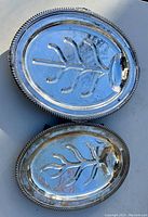 Photo showing two oval silver plated fish platters stacked with fish bone embossed design and decorative beaded edges.