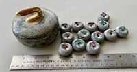 Curled stone porcelain box with 12 small porcelain stones and measuring ruler for scale.