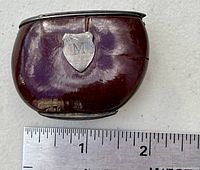 Top and front view of the antique box showing the monogrammed sterling silver shield with the letter 'M' along with visible surface wear and sizing reference scale.