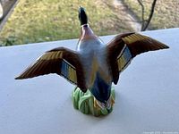 Porcelain duck figurine with wings fully extended, viewed from the top showing detailed coloring.