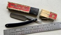 Photo of vintage straight razor laid out next to a ruler and original boxes showing condition and size.