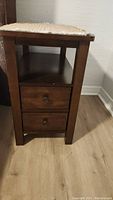Side view of wooden end table showing two drawers with round knobs and a lower shelf.