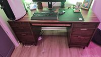Full front view of the wooden desk showing seven drawers and desktop with keyboard, mouse, and monitor.