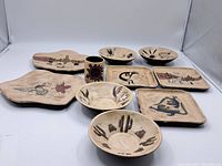 All nine pieces of the ceramic dish set arranged together to show the variety and style of each dish and bowl with painted desert motifs.