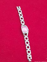 Full view of the Fossil F2 ladies' wristwatch on a red background showing linked stainless steel bracelet and pink dial.