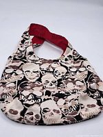 Front view of vintage fabric hand bag showing skull pattern and red lining inside the strap
