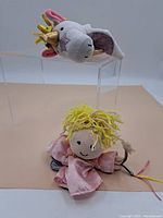 Photo showing both hand puppets - unicorn and girl on beige and clear acrylic riser background