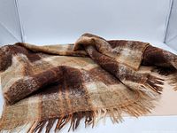 Soft mohair scarf folded, showing the plaid pattern and fringed edges.