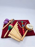 Top view of the lot with various small traditional musical instruments placed on a red cloth pad