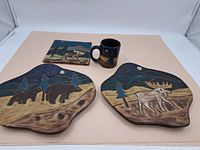 Overview of two pottery tiles and a mug with hand-painted wildlife designs on a beige background