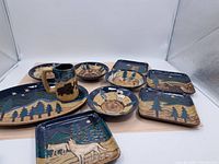 Full set of pottery dishes and mug arranged in a group showing various sizes and shapes with nature motifs