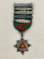 Full view of the safe driving award medal showing the star-shaped silver medal with colorful central emblem, attached green and orange striped ribbon, and five year bars marked 1937 to 1941.