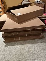 Stack of flat, bundled corrugated cardboard sheets with one assembled box on top