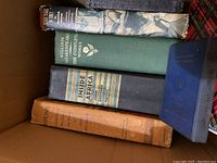 Box of five old hardcover books viewed from top, titles visible include Kipling, Shakespeare, and Inside of Africa.