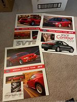 Lot of three Ford SVT car brochures from 1999, featuring Ford F-150 Lightning, Contour, and Mustang Cobra models, arranged on carpet.