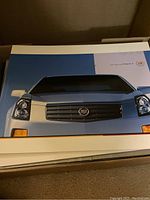 Box of Cadillac brochures featuring a Cadillac car front grille on the cover