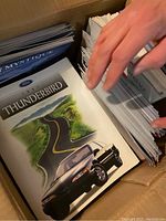 Box filled with neatly stacked brochures featuring the 1995 Ford Thunderbird on top.
