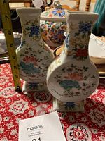 Front view of two Chinese porcelain vases with floral and leaf designs and a measuring tape showing height approximately 7 inches.