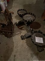 Photo showing large iron candelabra and old iron light fixture on concrete floor.
