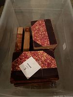 Set of thirteen books with leather and marbled covers inside plastic bin