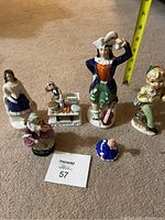 Overview photo of entire figurine lot with measuring tape showing height of tallest figure