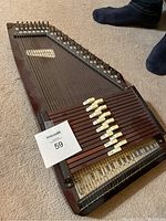 Full view of chromaharp showing dark wood body, strings, tuning pegs, and labeled levers with maxsold lot card.