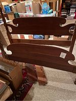 Photo of the solid wood antique bed frame showing headboard, footboard, and turned posts with traditional design details.