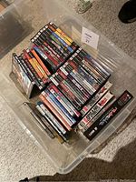 Plastic storage bin containing stacks of video game and DVD cases