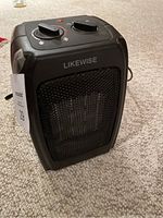 Front view of black Likewise branded electric space heater showing mesh grille and power settings label.
