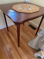 Full view of cherry wood square table with Bonanza game board and cards on top