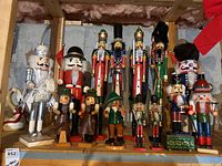 Shelf display showing 14 assorted Christmas nutcrackers of different heights and styles.